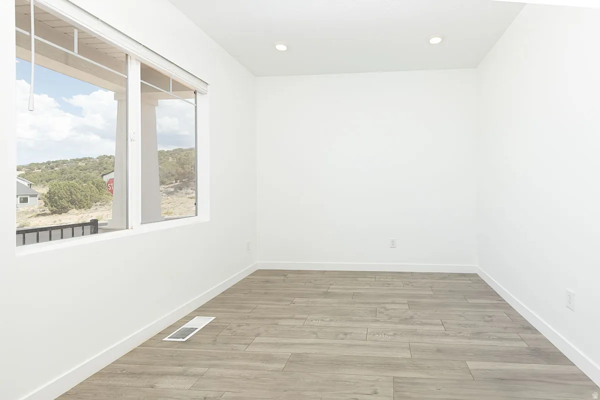 Recessed ceiling lighting, large window, wood-finish flooring, white walls, and white trim
