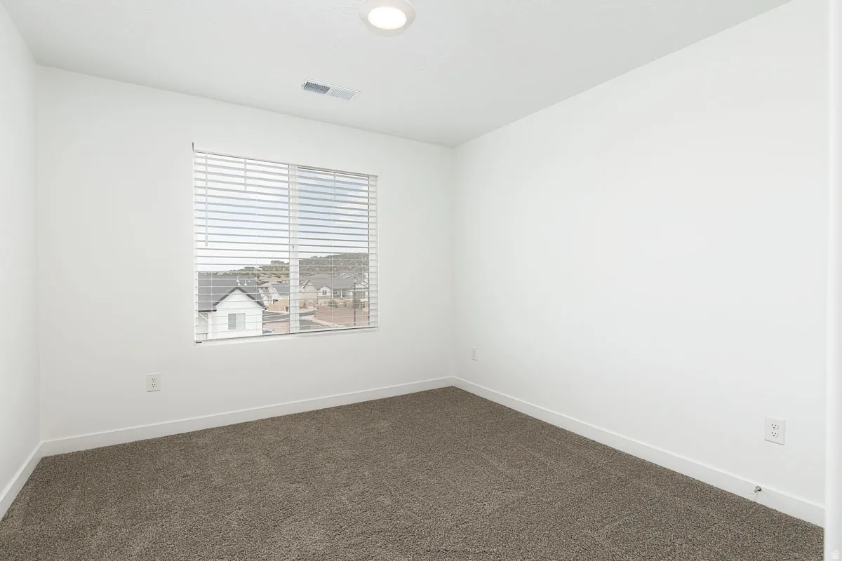 Neutral wall paint, textured carpeting, recessed ceiling lighting, and a single window with blinds