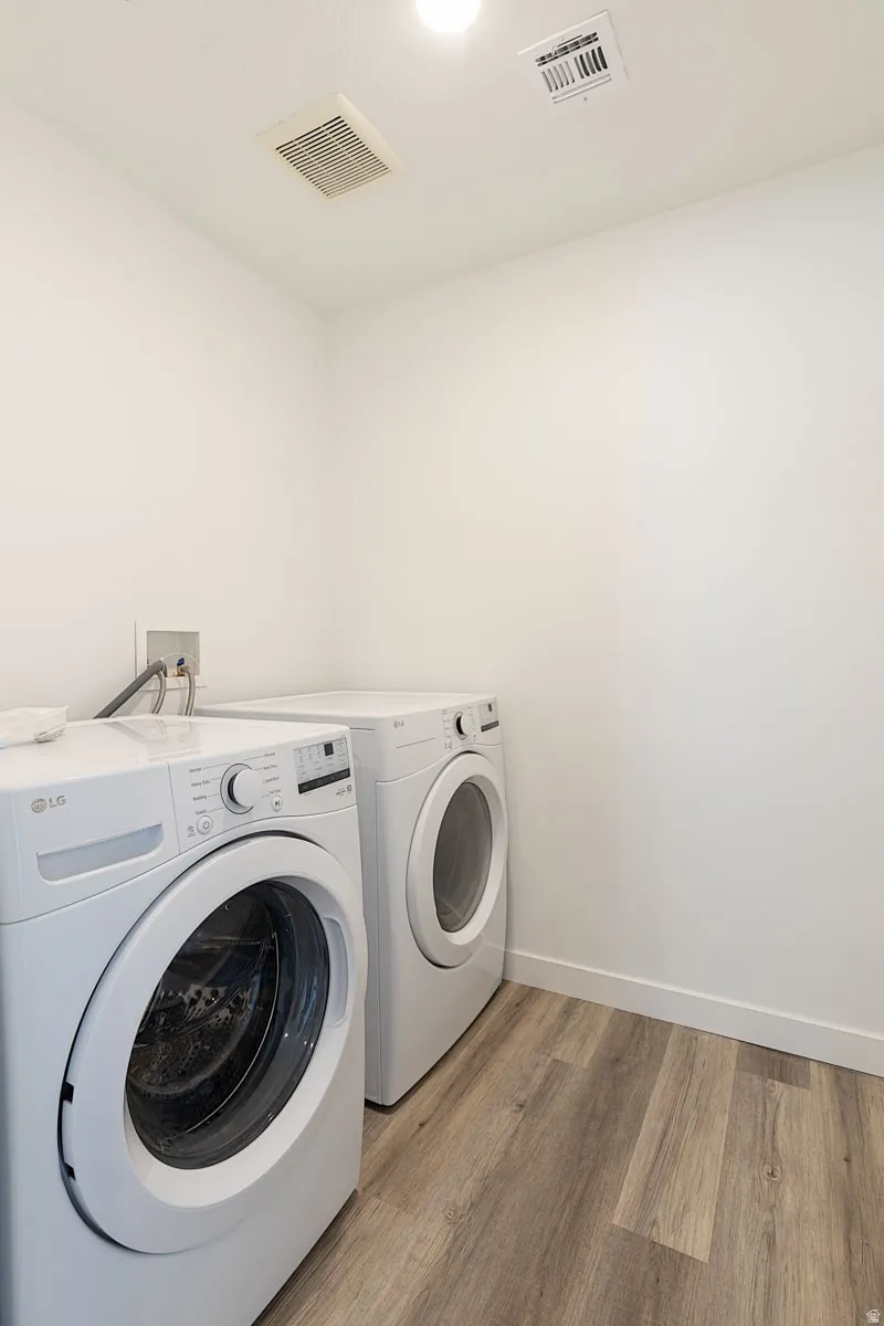 Dedicated laundry area with wood-finish flooring and essential utility connections