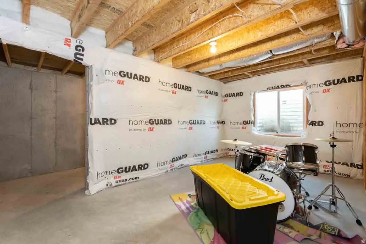 Unfinished basement with exposed ceiling joists, concrete floor, and window