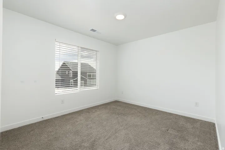 Neutral wall paint, recessed ceiling light, window with horizontal blinds, and carpeted flooring