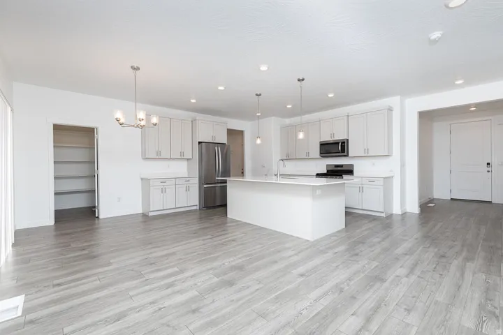 Spacious open-concept kitchen with wood-finish flooring, white cabinetry, a large kitchen island, and stainless steel appliances