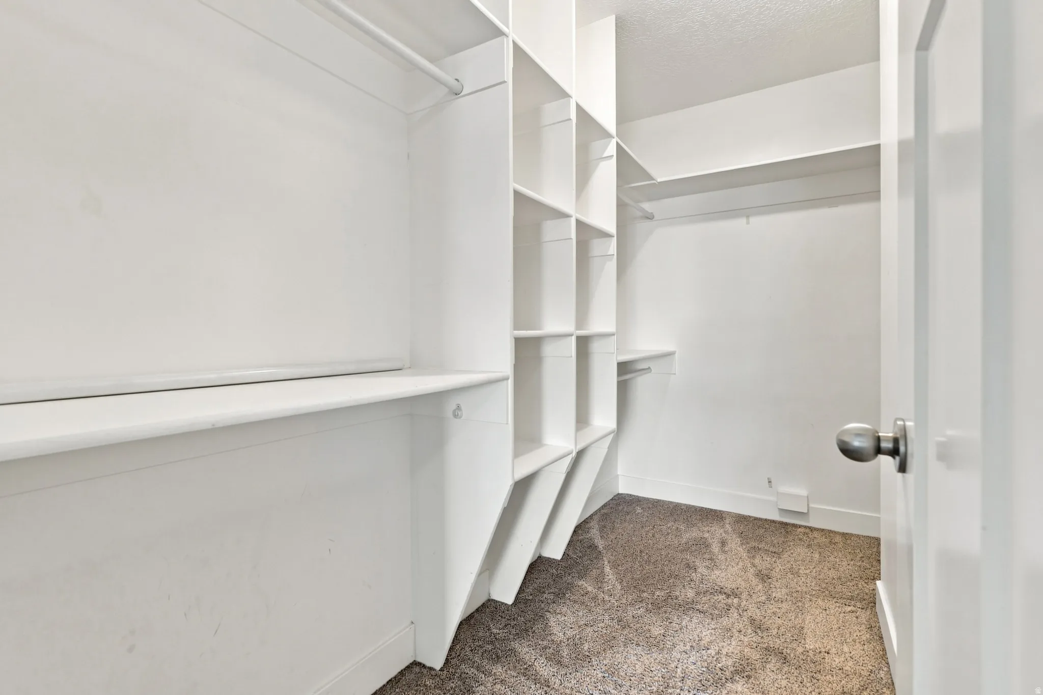 Integrated shelving system with multiple storage cubbies, white built-in shelving, and carpet flooring
