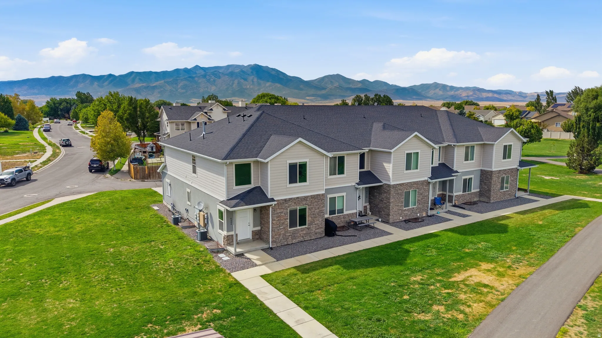 Multi-unit building featuring stone and siding exterior, dark shingle roof, and individual entryways