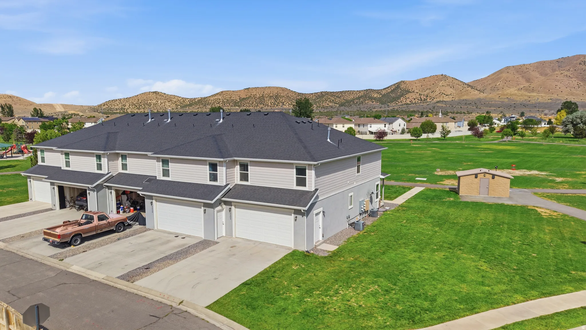 Multi-unit property featuring light-colored siding and dark shingle roofing