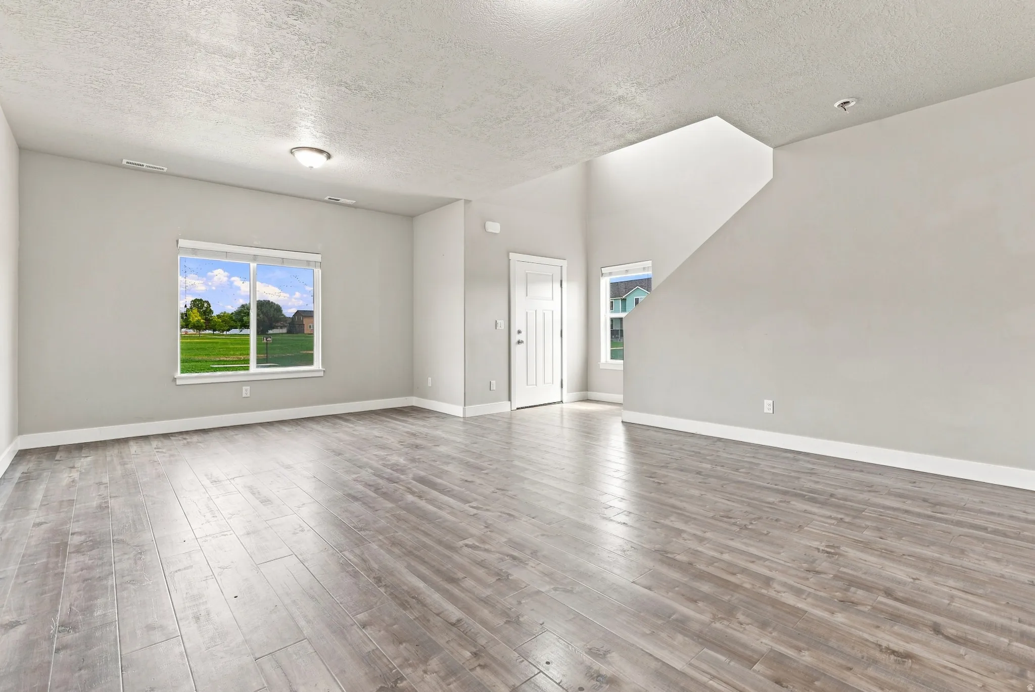 Spacious living area featuring wood-finish flooring, recessed lighting, and large windows