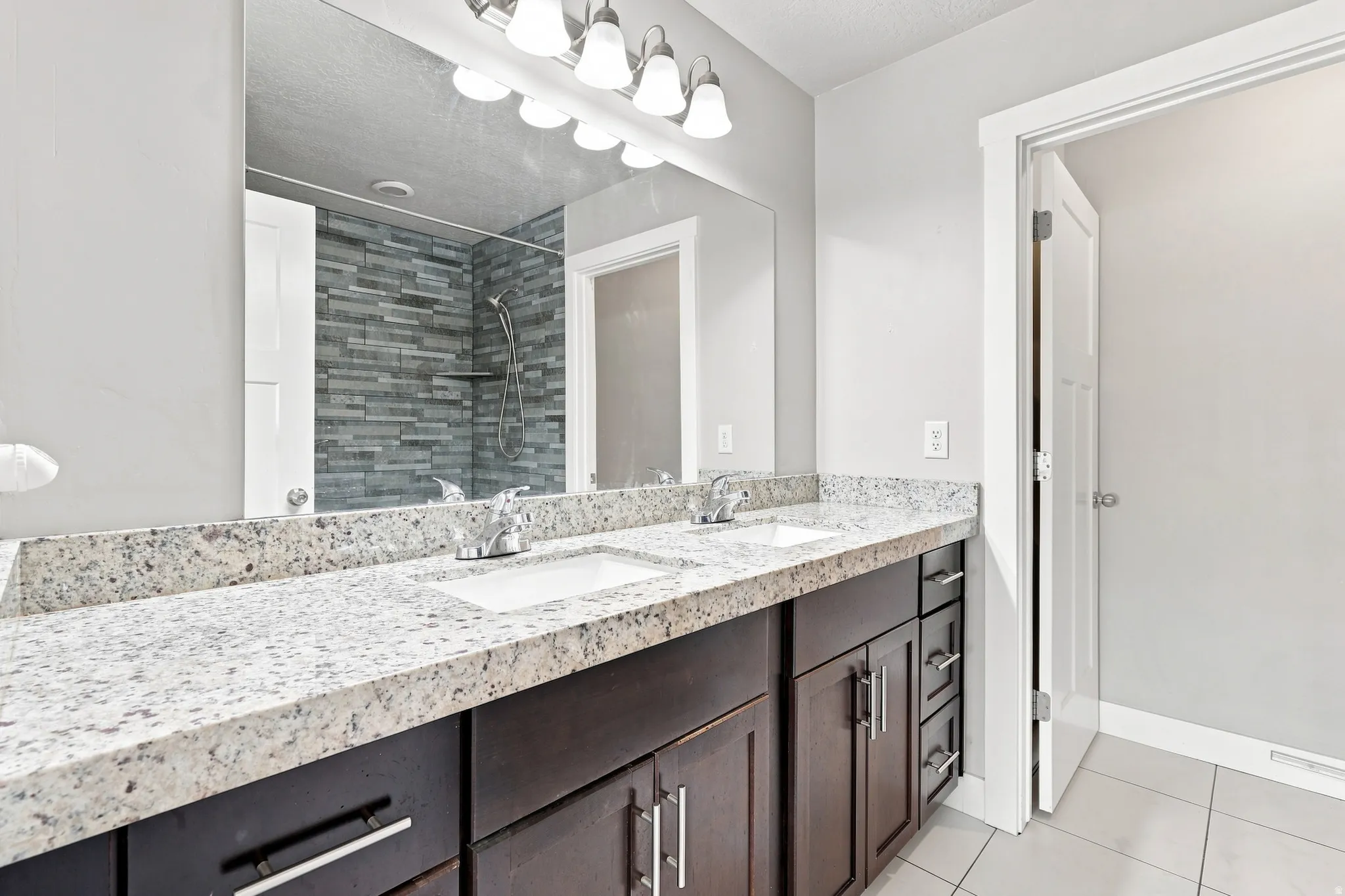 Double vanity with undermount sinks, speckled stone countertop, and dark wood-finish cabinetry
