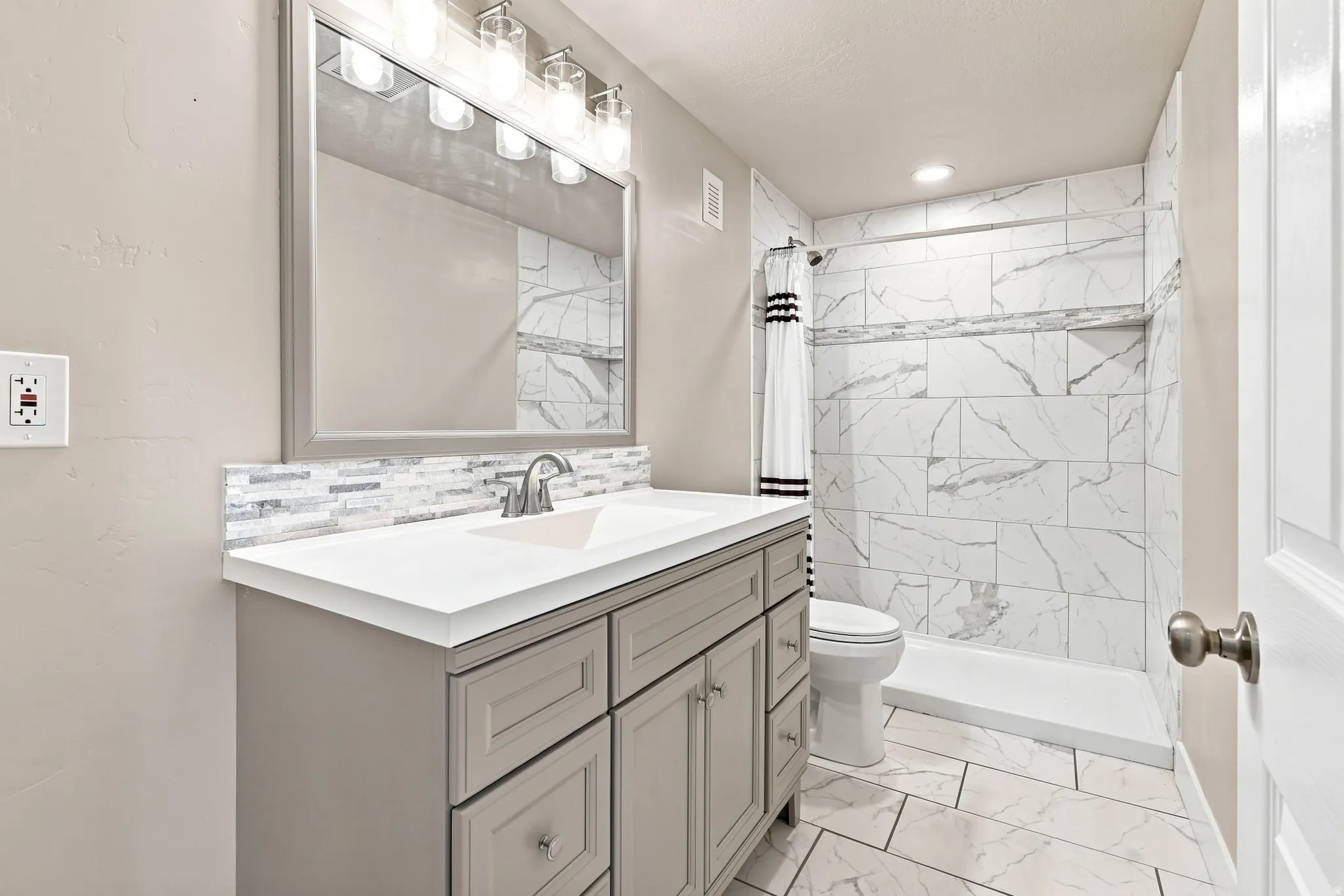 Modern vanity with a dual sink, sleek countertop, and a mosaic tile backsplash