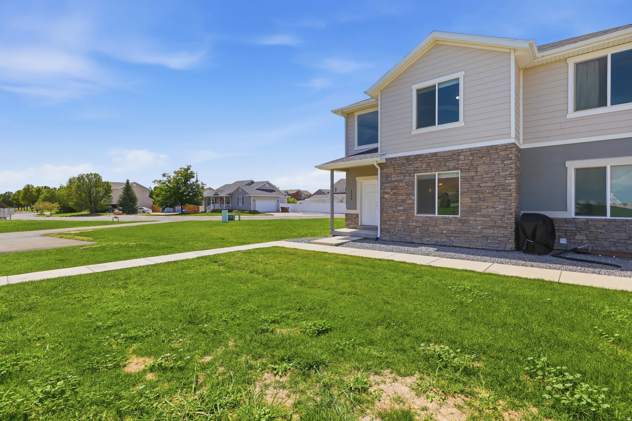 Multi-level exterior with light-colored siding and stone-veneer accents