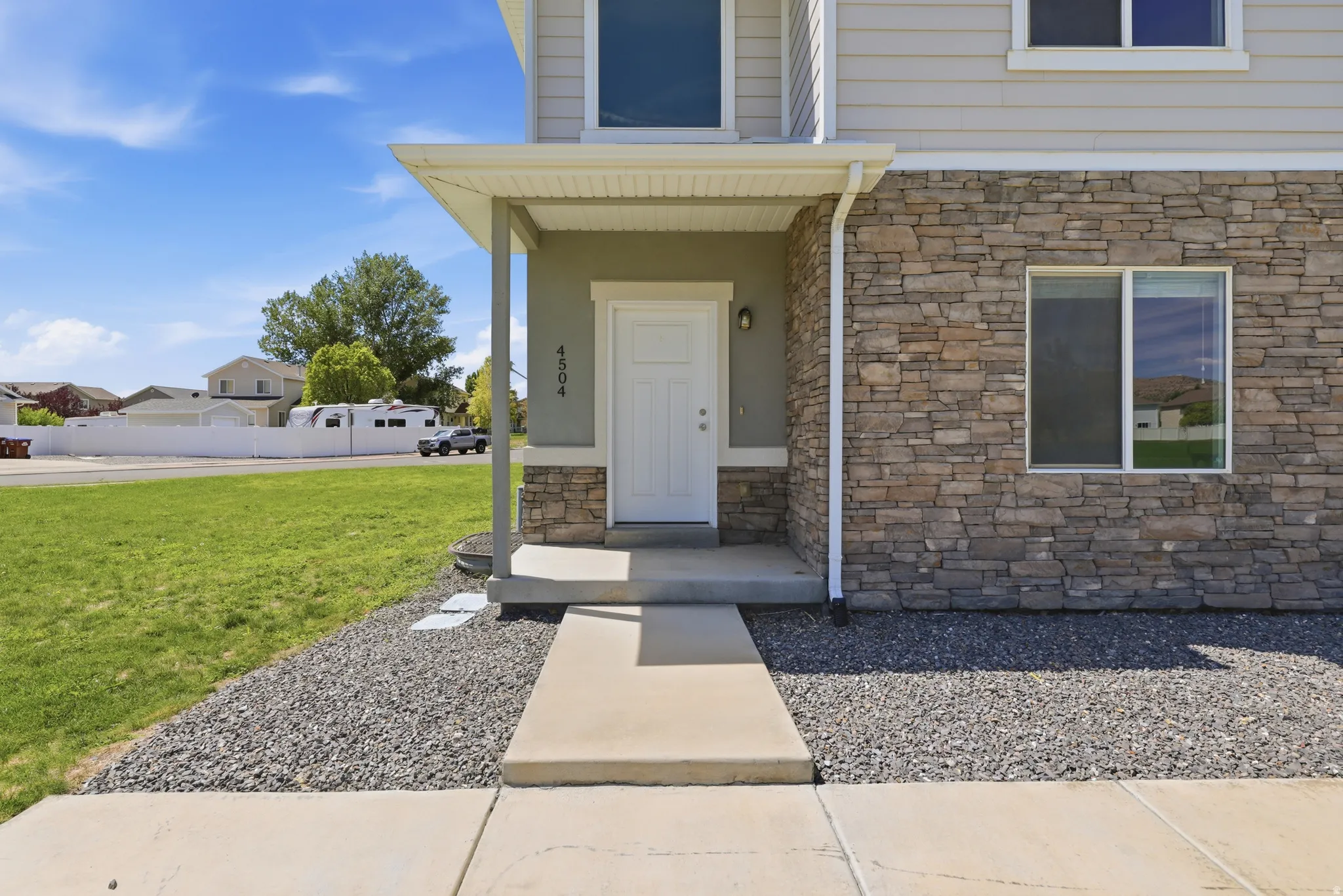 Stone veneer accents on the facade, covered entryway, and concrete walkway