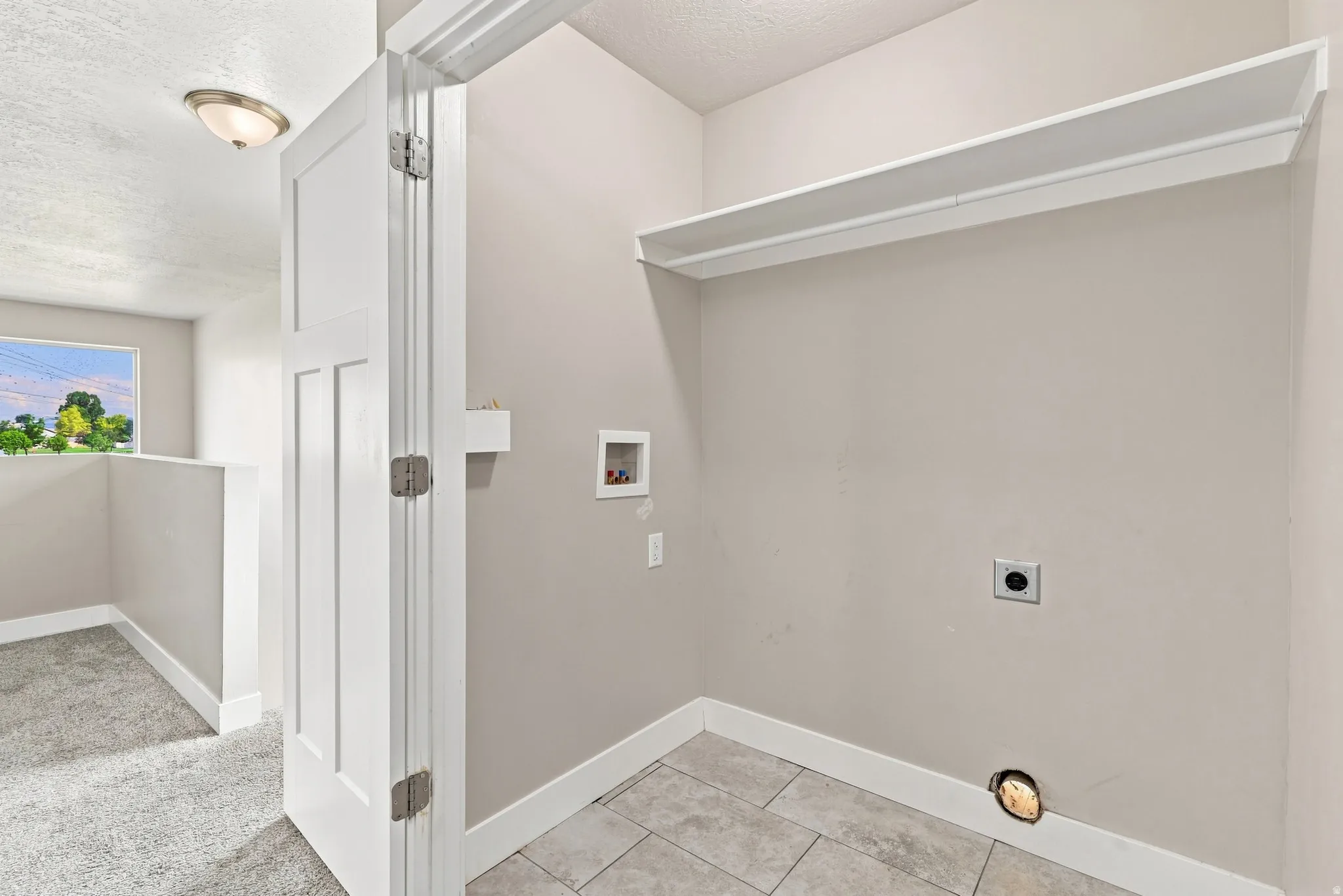 Dedicated laundry area featuring a built-in shelf, appliance hookups, and tiled flooring