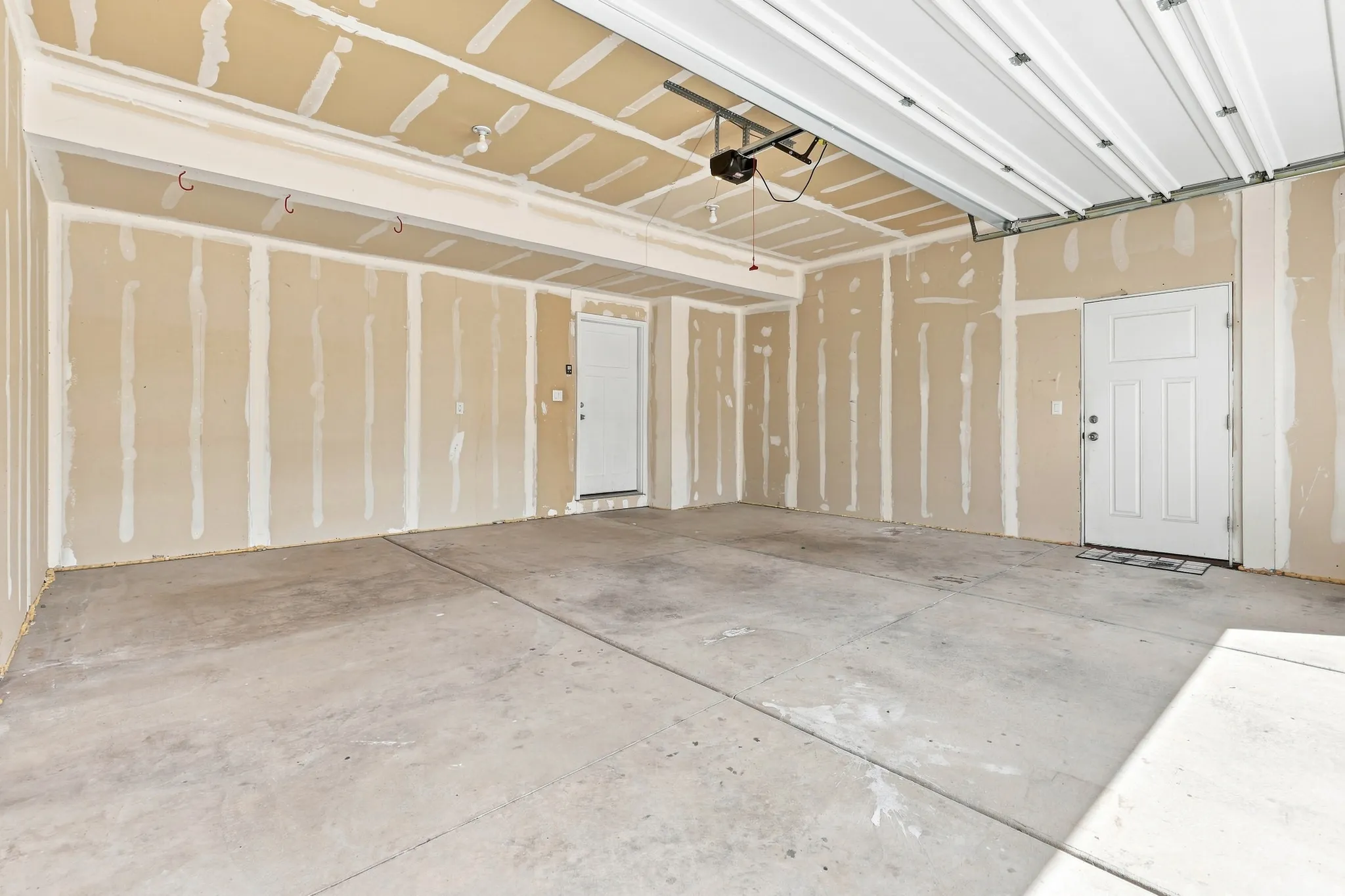 Spacious garage with unfinished walls, concrete flooring, and an overhead garage door