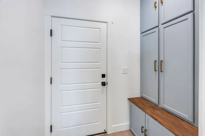 Paneled interior door with dark hardware, built-in cabinetry with wood-finish countertop, and brass-tone hardware