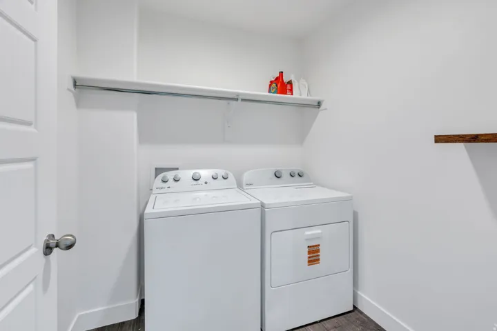 Dedicated laundry area featuring a built-in shelf, hanging rod, and dark wood-finish flooring