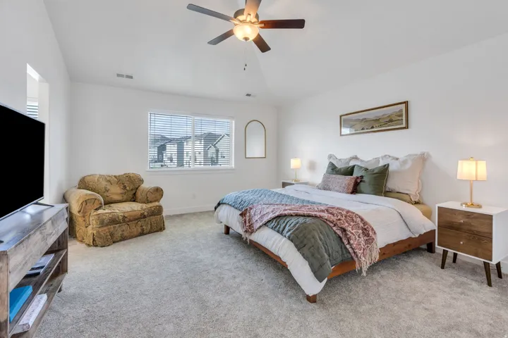 Wall-to-wall carpeting with a ceiling fan light fixture, large window with horizontal blinds, and a built-in wall niche