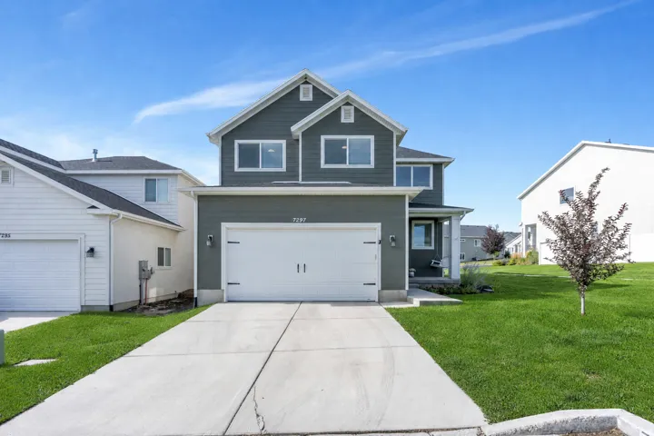 Two-story exterior with dark grey siding, white trim, a two-car garage, and a concrete driveway