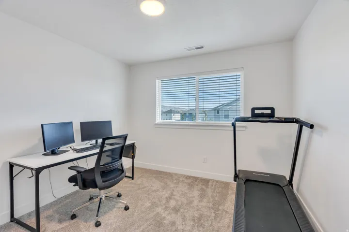 Plush carpet flooring, white walls, and a window with blinds