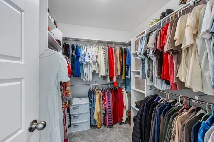 Walk-in closet featuring extensive built-in shelving, multiple hanging rods, and recessed lighting