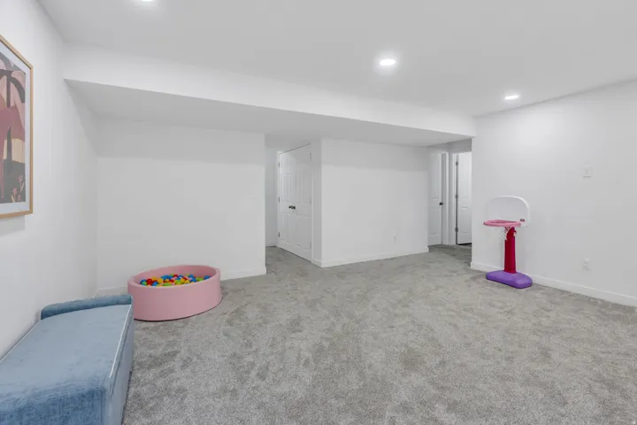 Recessed lighting, light gray carpet flooring, white painted walls, white trim, and a white paneled door