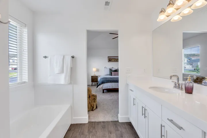 Bathroom featuring a single vanity with a white countertop, built-in cabinetry, a bathtub with a shower combination, and wood-finish flooring
