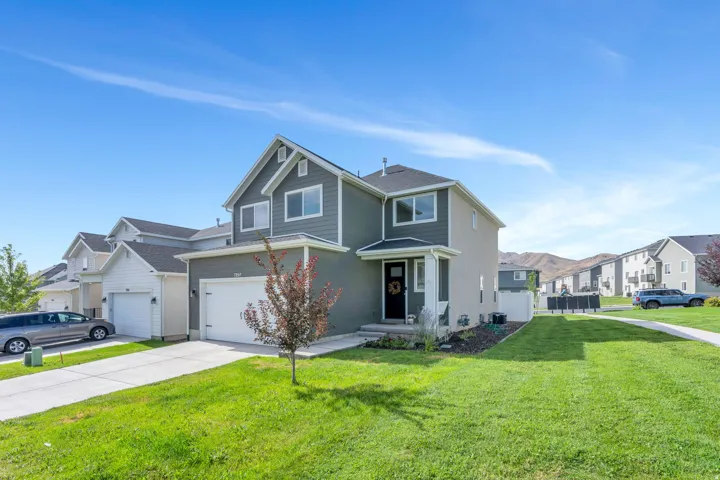 Two-story residence featuring a two-car garage, gray siding, a covered front entry, and a paved driveway