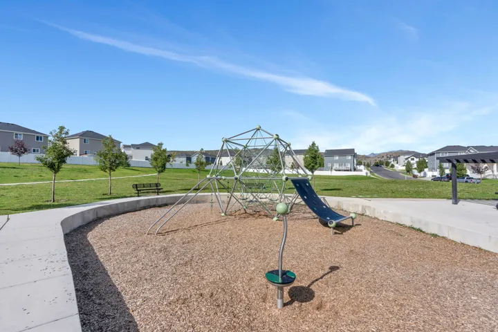 Community playground featuring a geometric climbing structure, slide, and wood chip ground cover