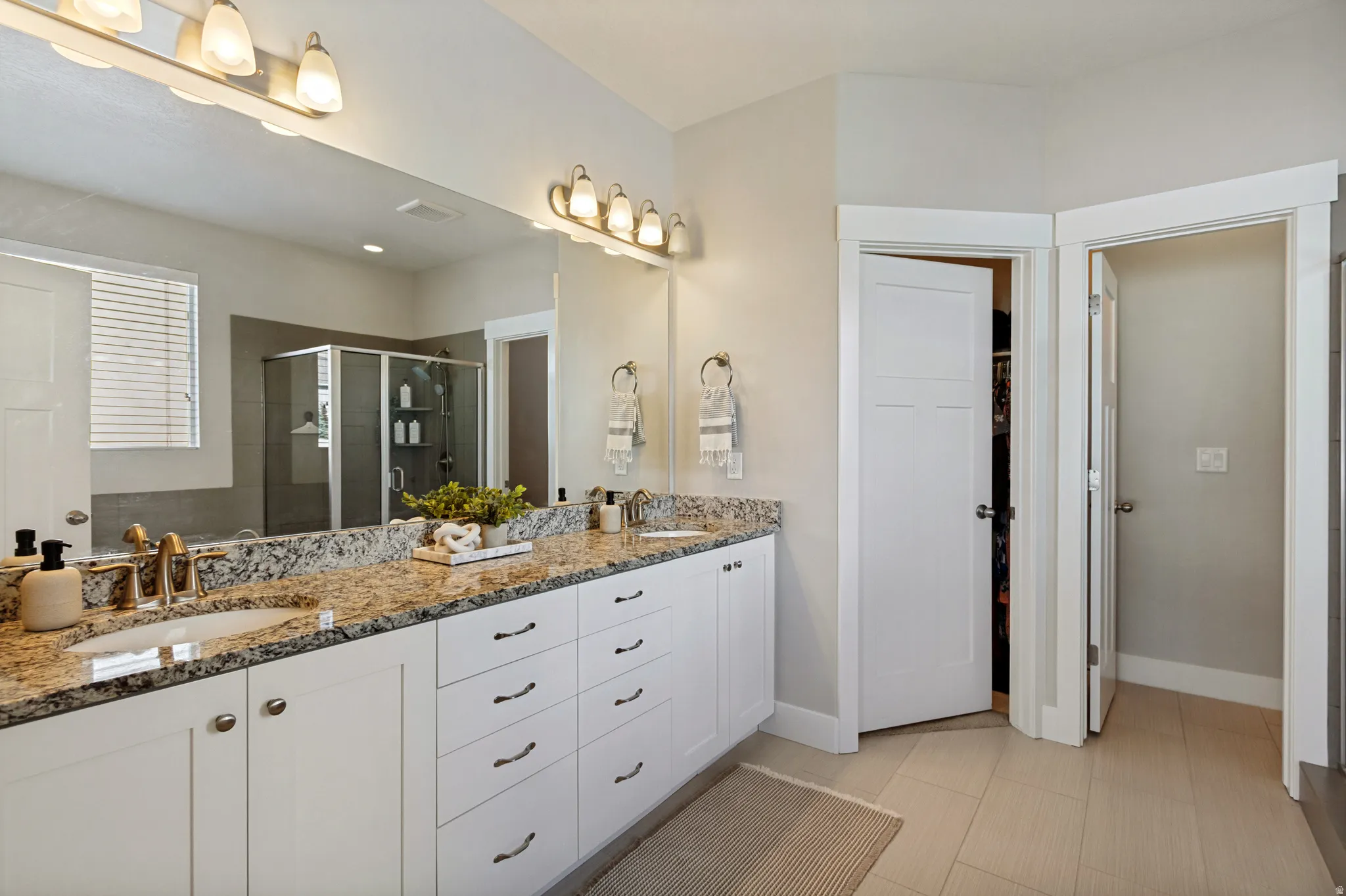 Dual sink vanity with granite countertop, white cabinetry, and brushed nickel fixtures