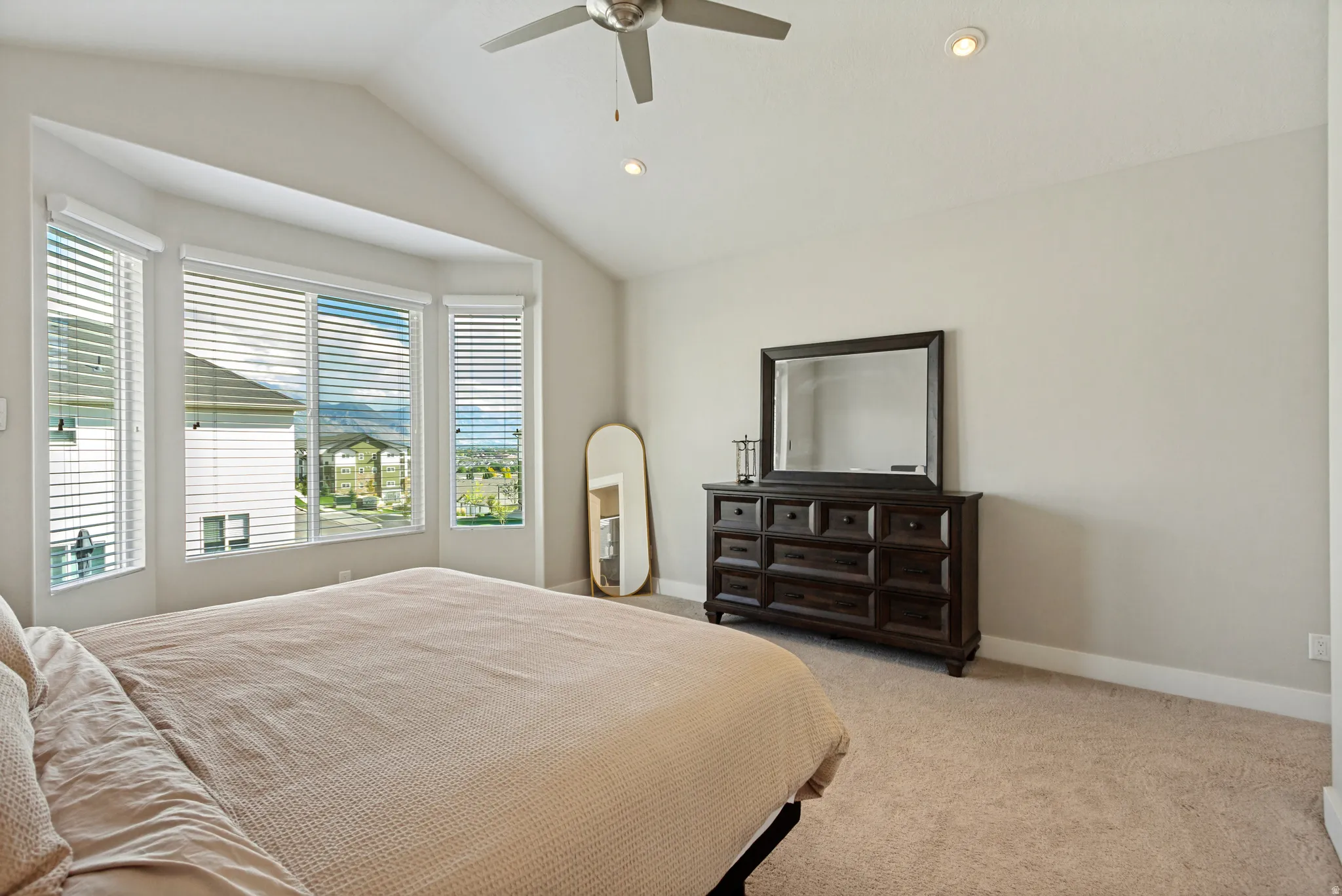 Vaulted ceiling with a ceiling fan and recessed lighting, multiple windows with blinds, and neutral carpet flooring