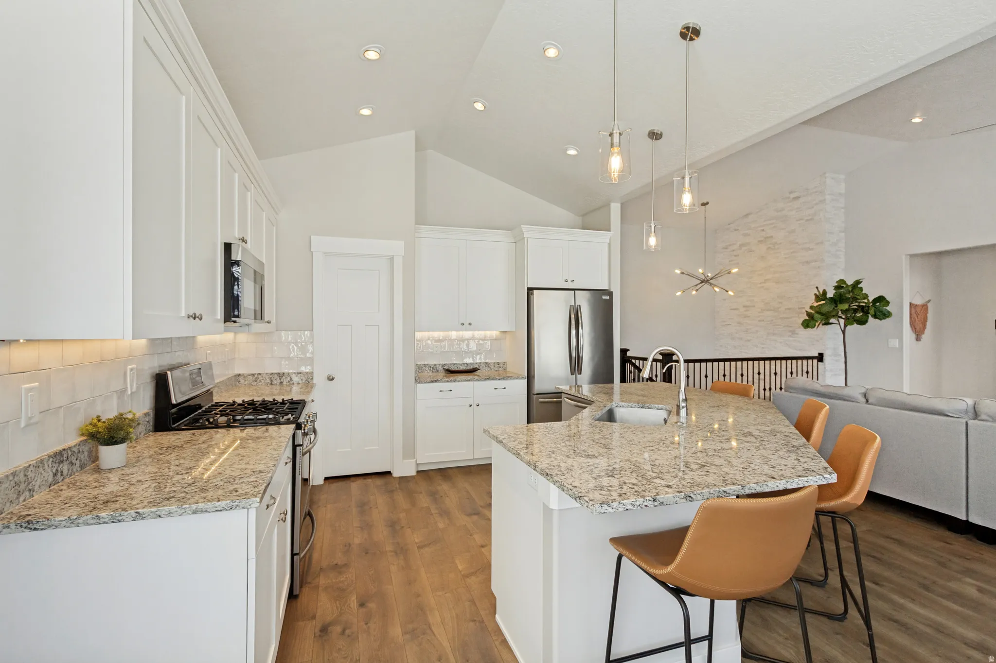 White shaker cabinetry with under-cabinet lighting, stainless steel appliances, a gas range, and a large kitchen island with an undermount sink