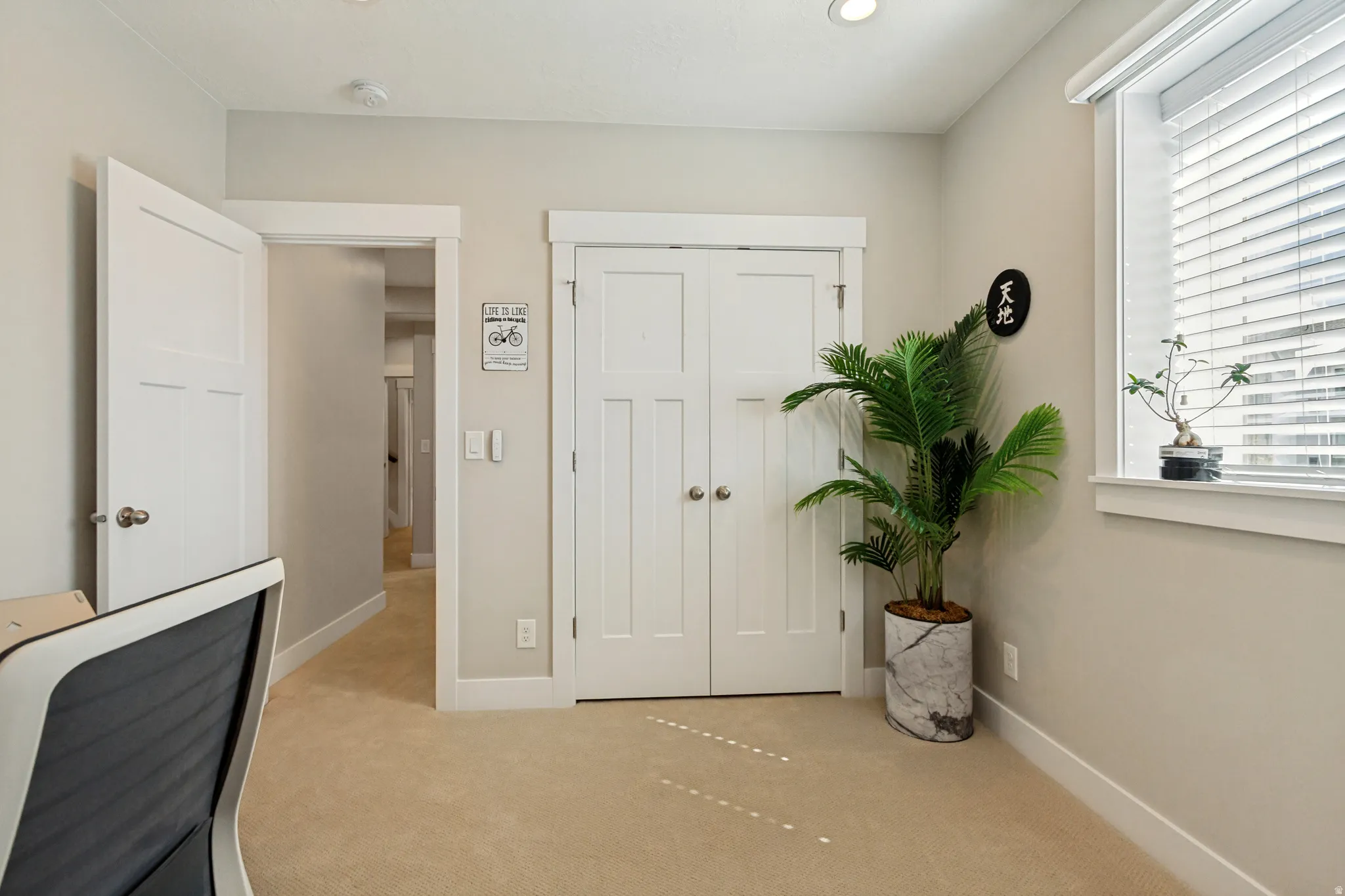 Carpeted room with white trim, a double-door closet, and a window with blinds