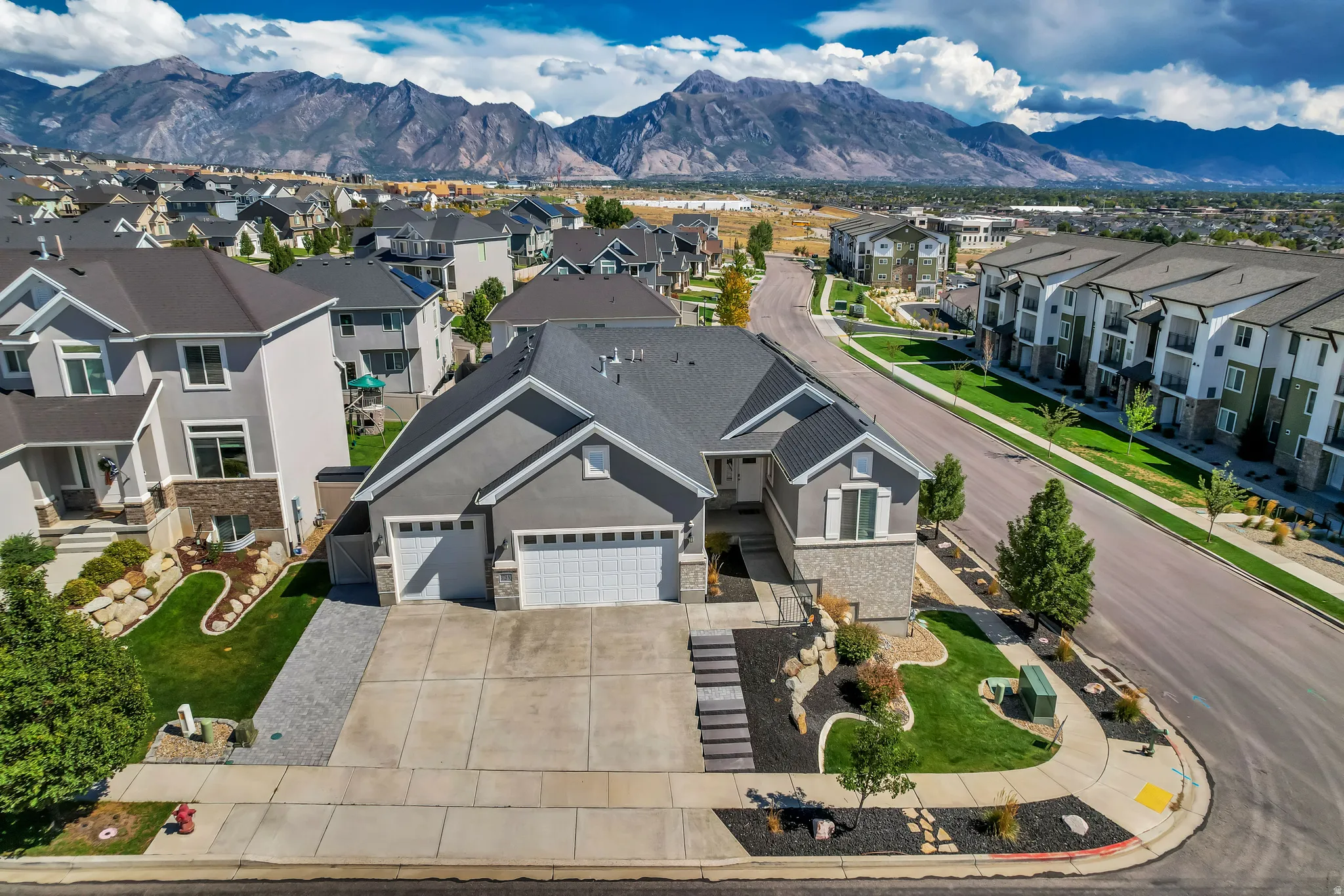 Modern stucco exterior with stone accents, an attached two-car garage, and established landscaping