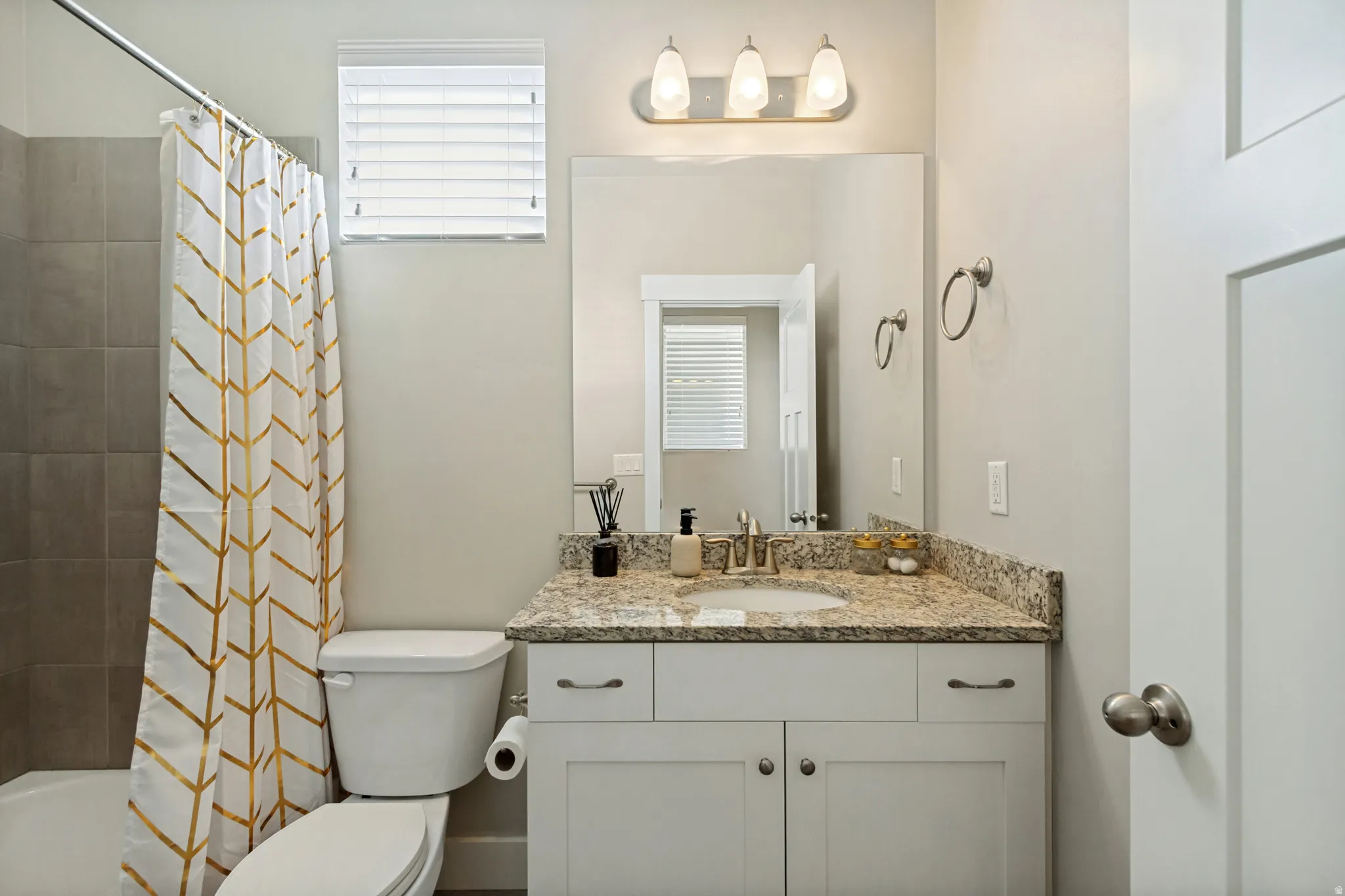 Single vanity with a granite countertop, undermount sink, and white cabinetry