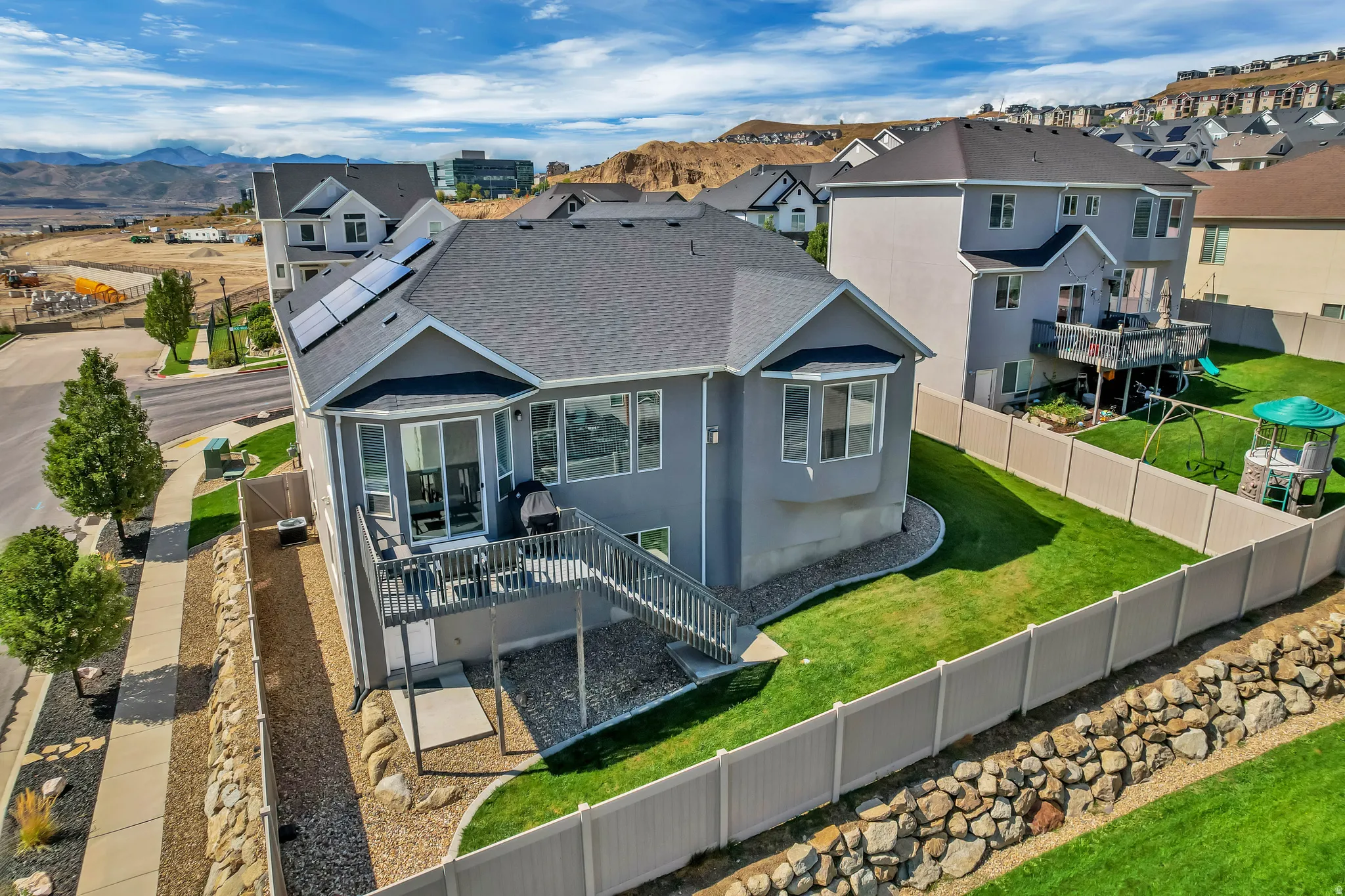 Exterior featuring solar panels, a private rear deck with stairs, and a bay window