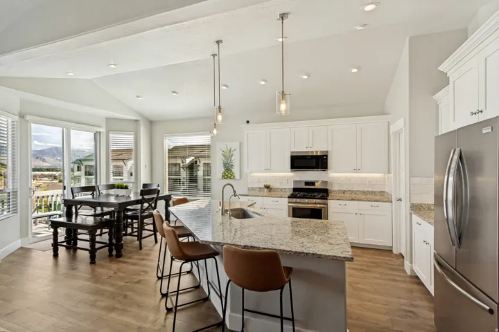 Kitchen featuring a vaulted ceiling, recessed lighting, white cabinetry, granite countertops, and stainless steel appliances