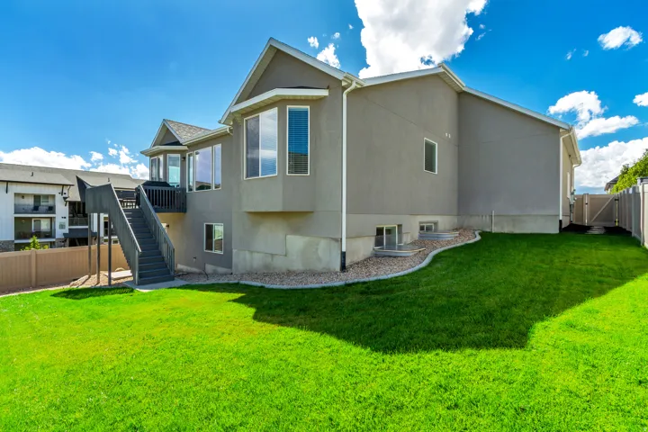 Spacious backyard featuring a manicured lawn, a multi-level deck with stairs, a privacy fence, and a gate