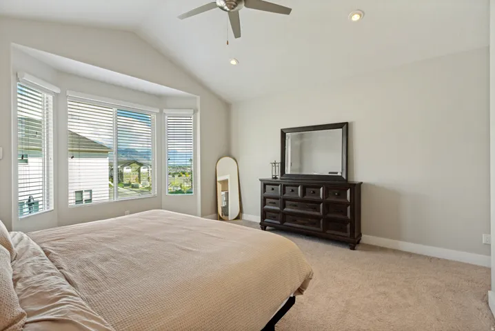 Vaulted ceiling with a ceiling fan and recessed lighting, multiple windows with blinds, and neutral carpet flooring