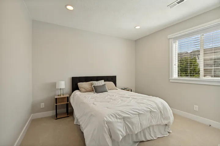 Recessed lighting, neutral wall tones, carpeted flooring, and a window with blinds