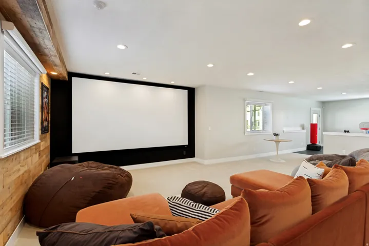 Large projection screen with an adjacent window, recessed lighting, and wall-mounted shelving