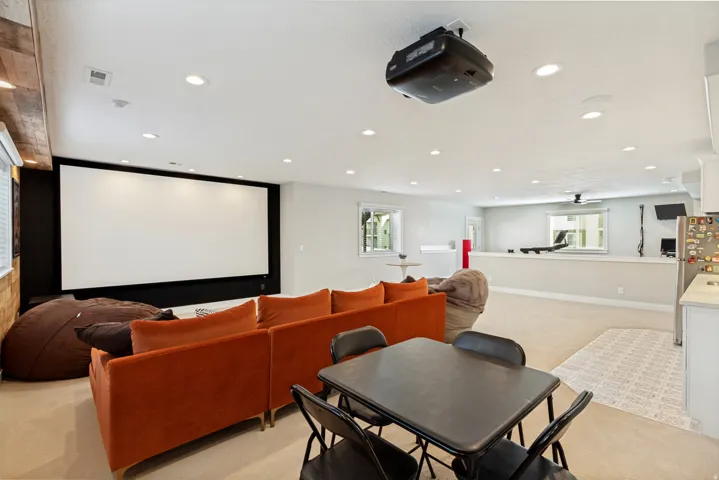 Recessed ceiling lighting, large projector screen, ceiling-mounted projector, built-in shelving, and light-toned carpeting