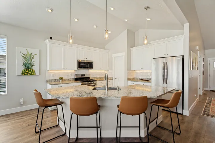 Kitchen with white cabinetry, stainless steel appliances, speckled stone countertops, and wood-finish flooring