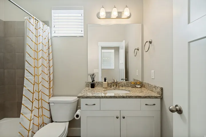 Single vanity with a granite countertop, undermount sink, and white cabinetry
