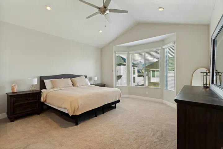 Vaulted ceiling with recessed lighting and ceiling fan, bay window with blinds, and wall-to-wall carpeting