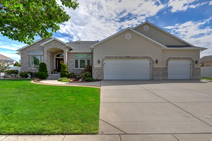 Stone veneer and stucco exterior, arched entry, bay windows, dual garage doors, and a concrete driveway