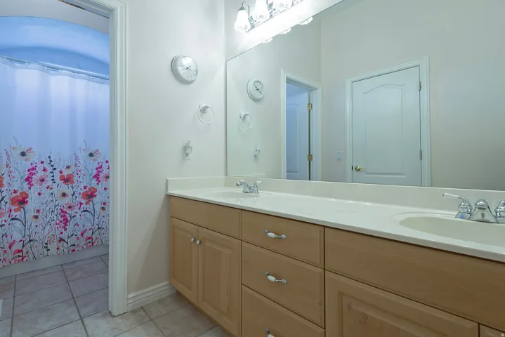 Double vanity with integrated sinks, chrome faucets, and light wood-finish cabinetry