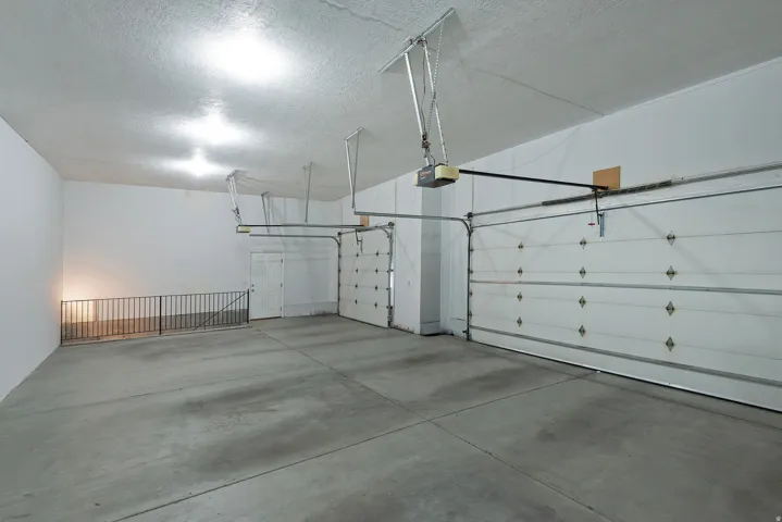 Spacious garage featuring a concrete floor, two overhead garage doors, an internal door, and overhead lighting fixtures