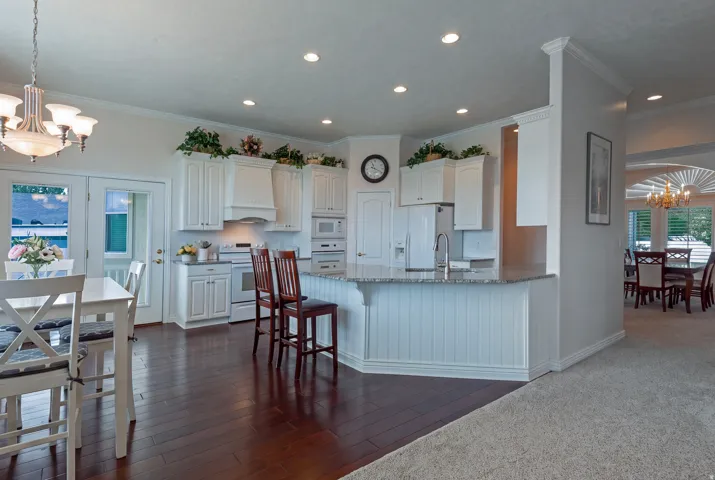Kitchen featuring white cabinetry, built-in appliances, recessed lighting, and a peninsula with countertop seating
