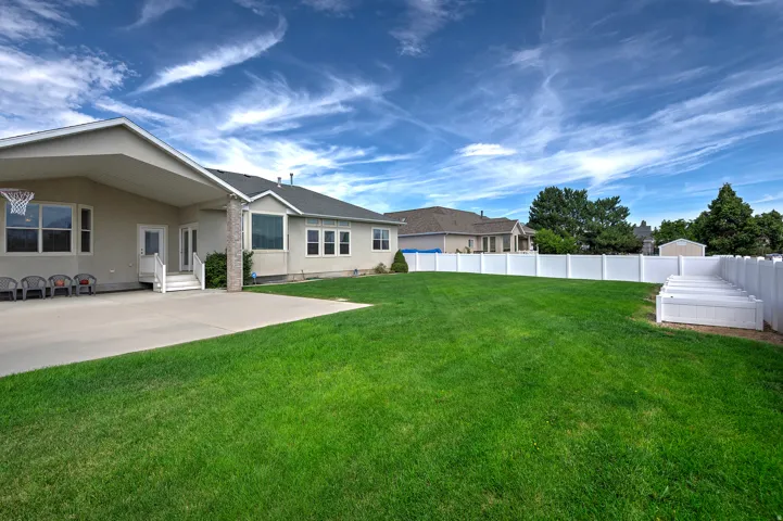 Expansive green lawn with a white privacy fence and raised garden beds