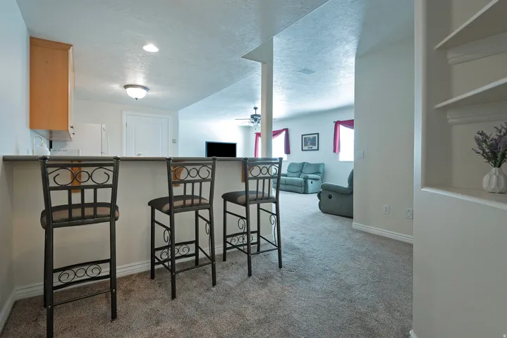 Carpeted flooring, built-in shelving, recessed lighting, ceiling fan, and light wood-finish cabinetry