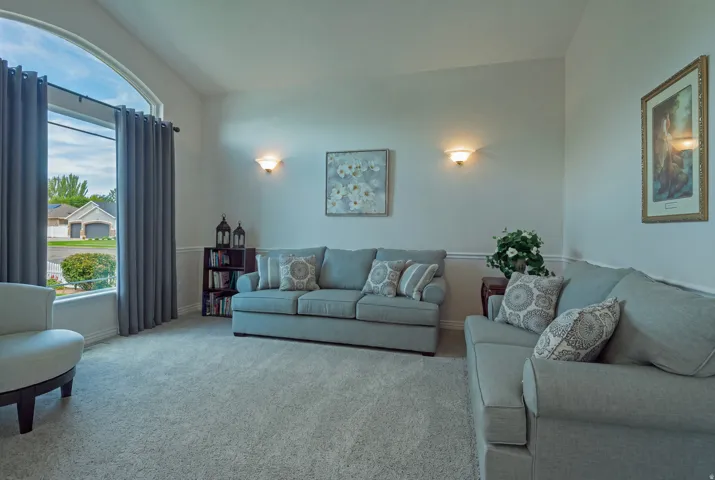 Arch-top window, vaulted ceiling, light-toned carpeting, wall sconces, chair rail molding