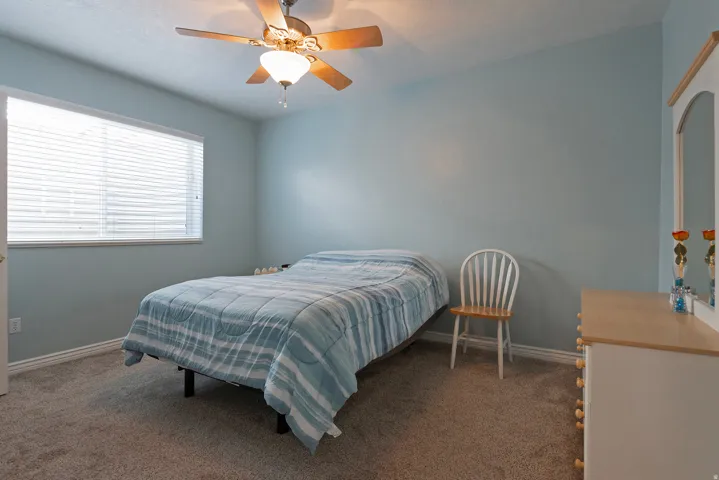 Carpeted flooring, window with blinds, ceiling fan with integrated lighting, light-toned wall paint